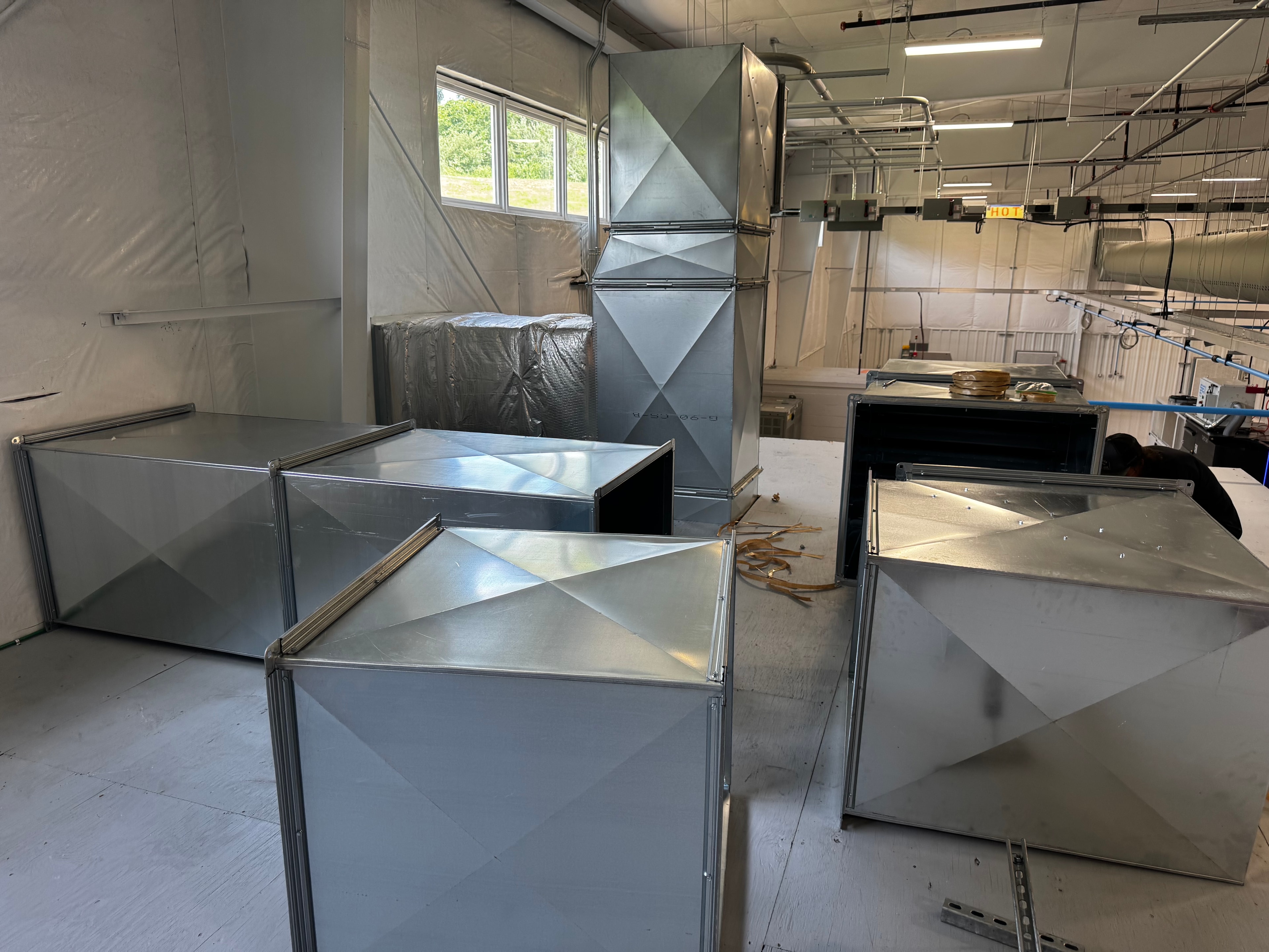 Custom sheet metal duct sections and plenum boxes staged on fabrication floor before installation — Monroeville commercial HVAC project