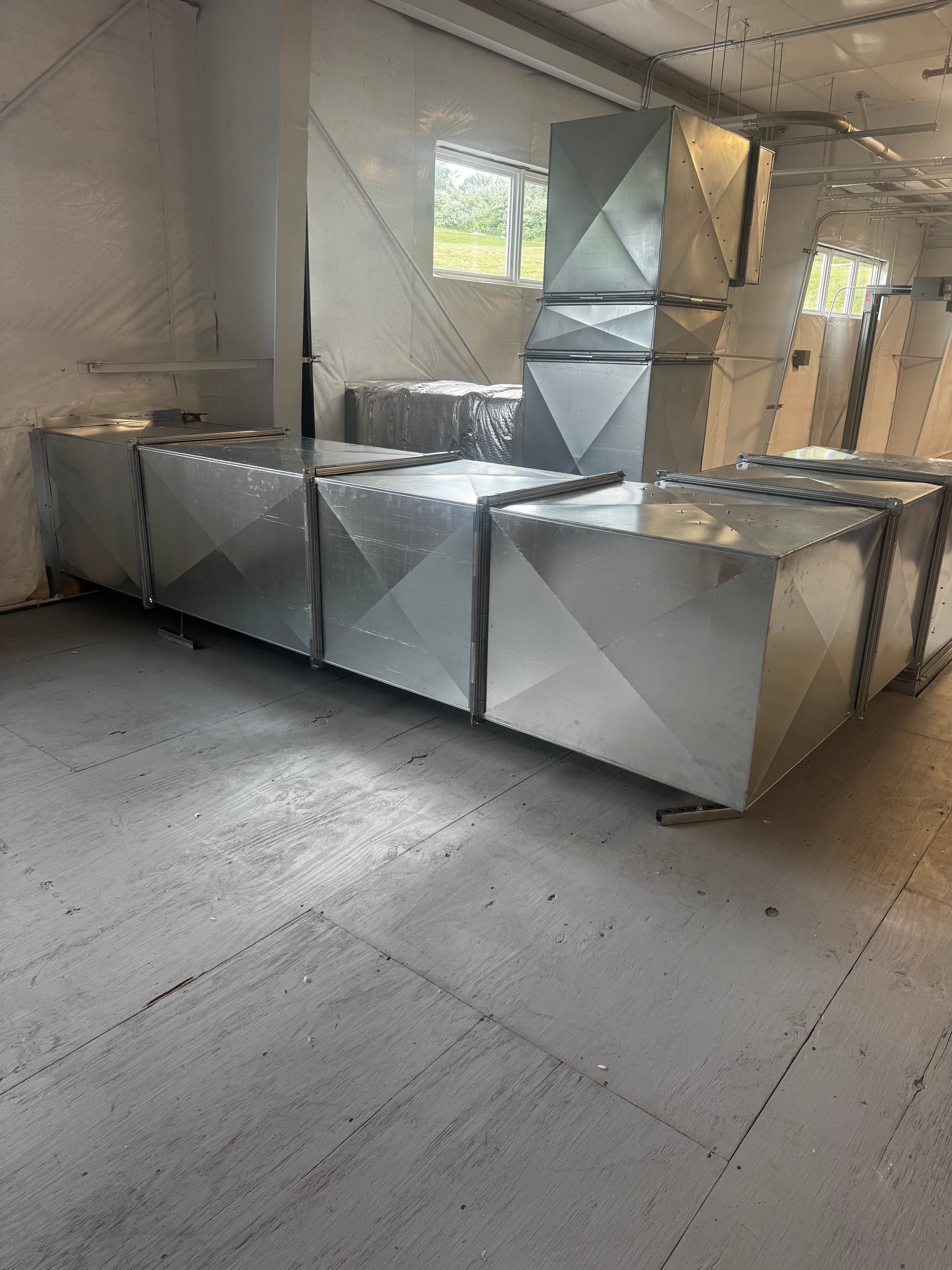 Large custom sheet metal trunk duct run installed along commercial facility wall — Monroeville, PA industrial HVAC project