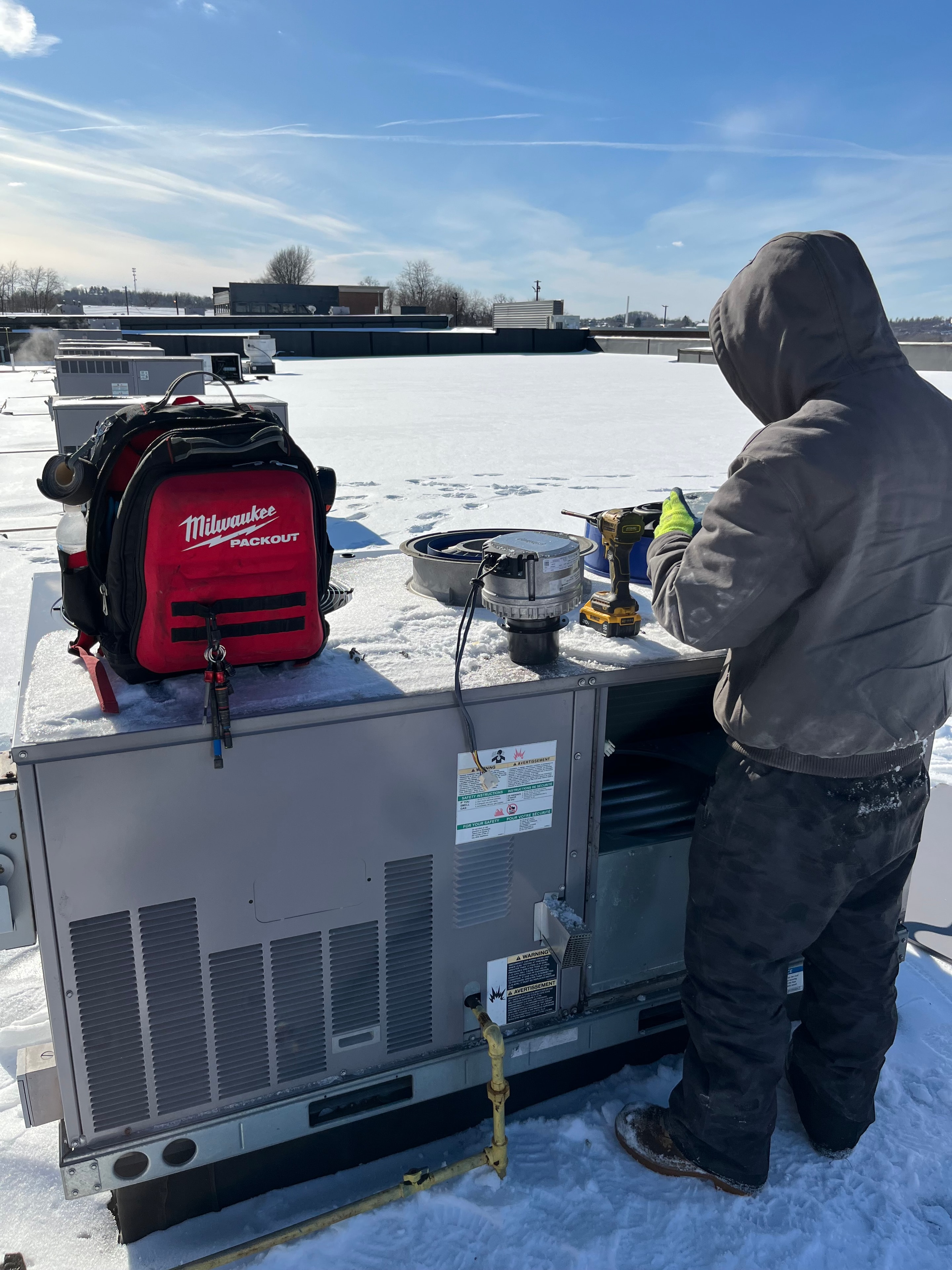 Heirloom Mechanical technician servicing a commercial packaged rooftop unit in Uniontown during winter